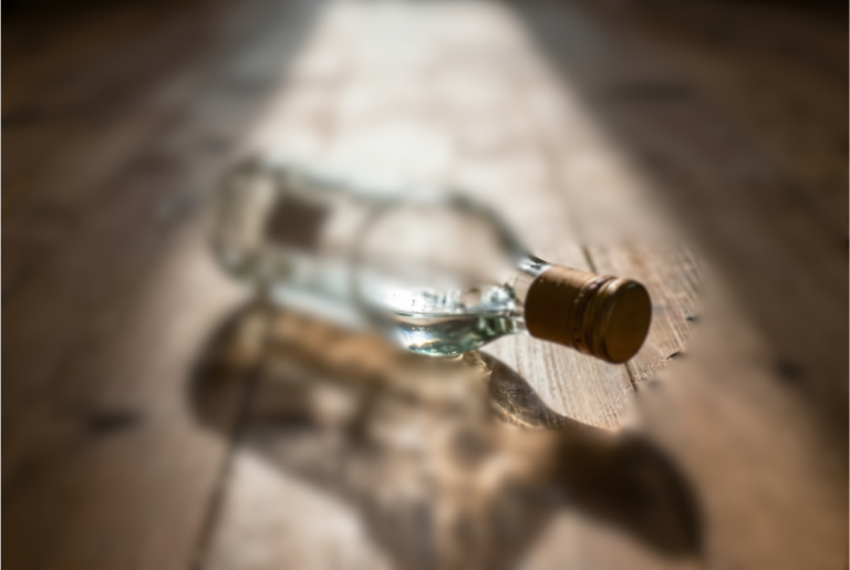 Bouteille en verre couchée sur une table en bois dans une lumière douce